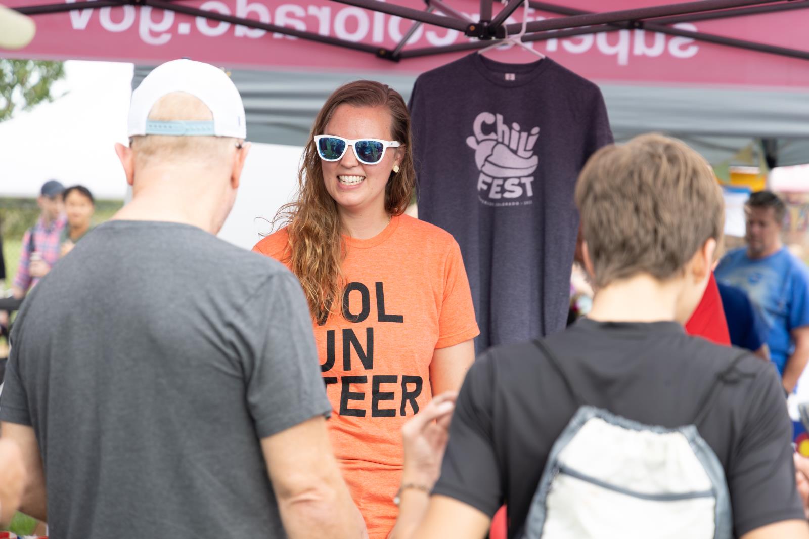 A volunteer helping to people under a tent at the chili and 2022 beer fest