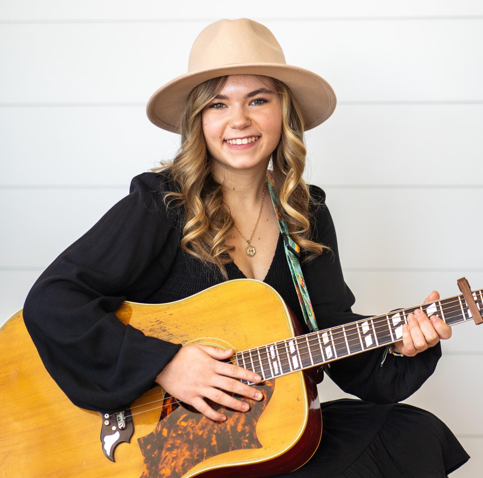 Professional headshot of national anthem singer Callie Laurine holding a guitar.