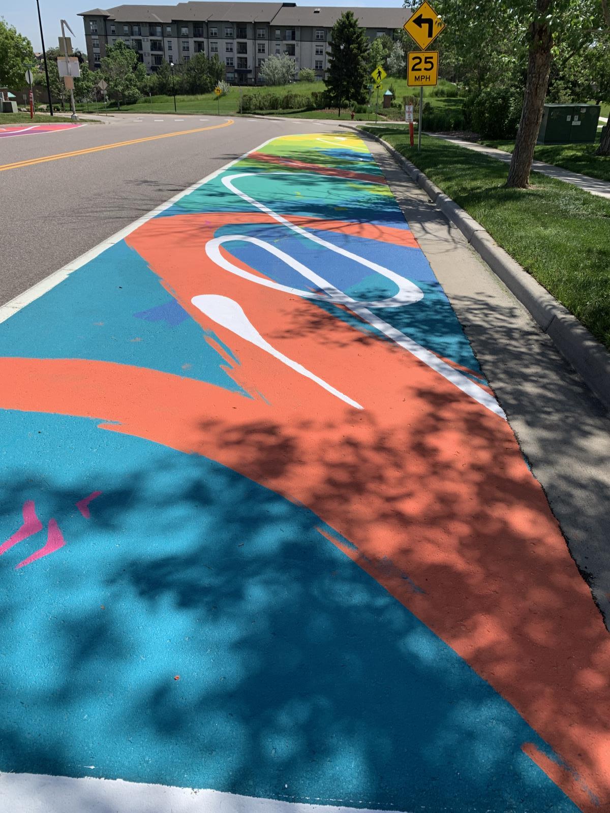 Graphic shapes in blues and oranges painted in a no-parking zone on the street