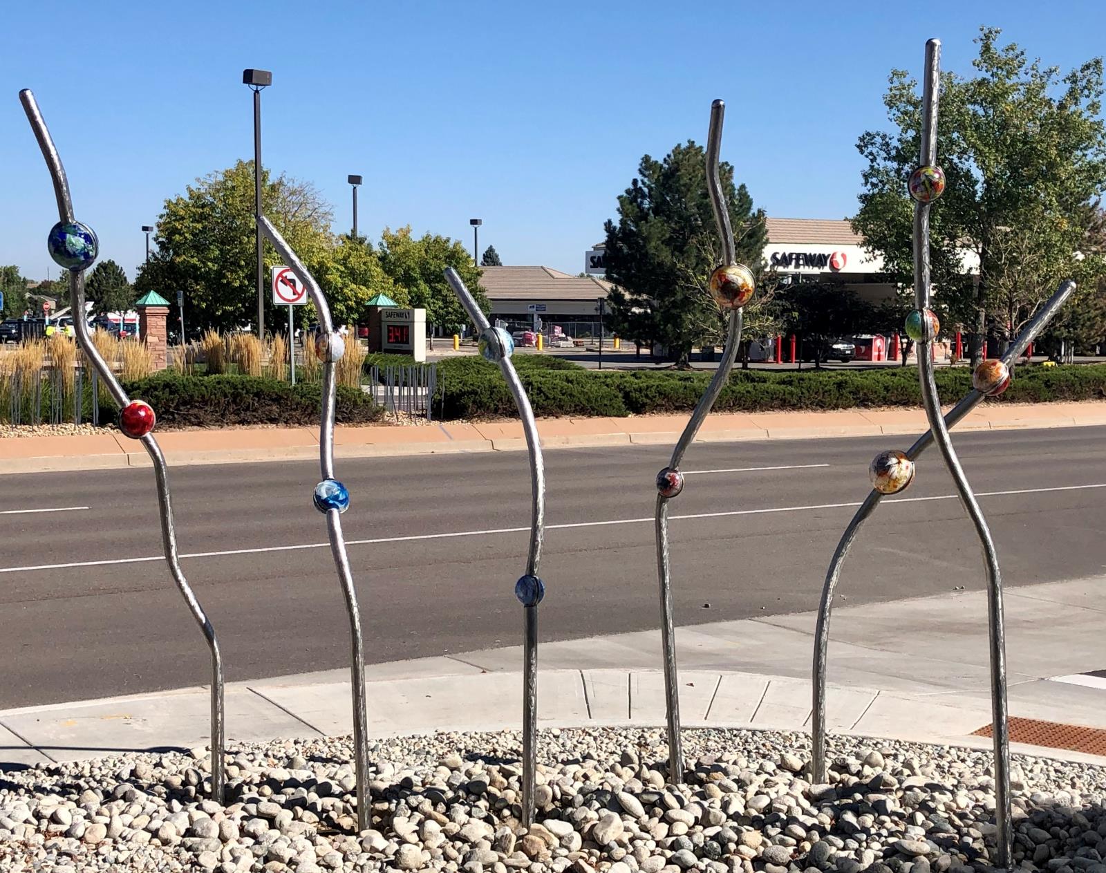 Seven stainless steel poles in whimsical shapes with blown glass orbs attached