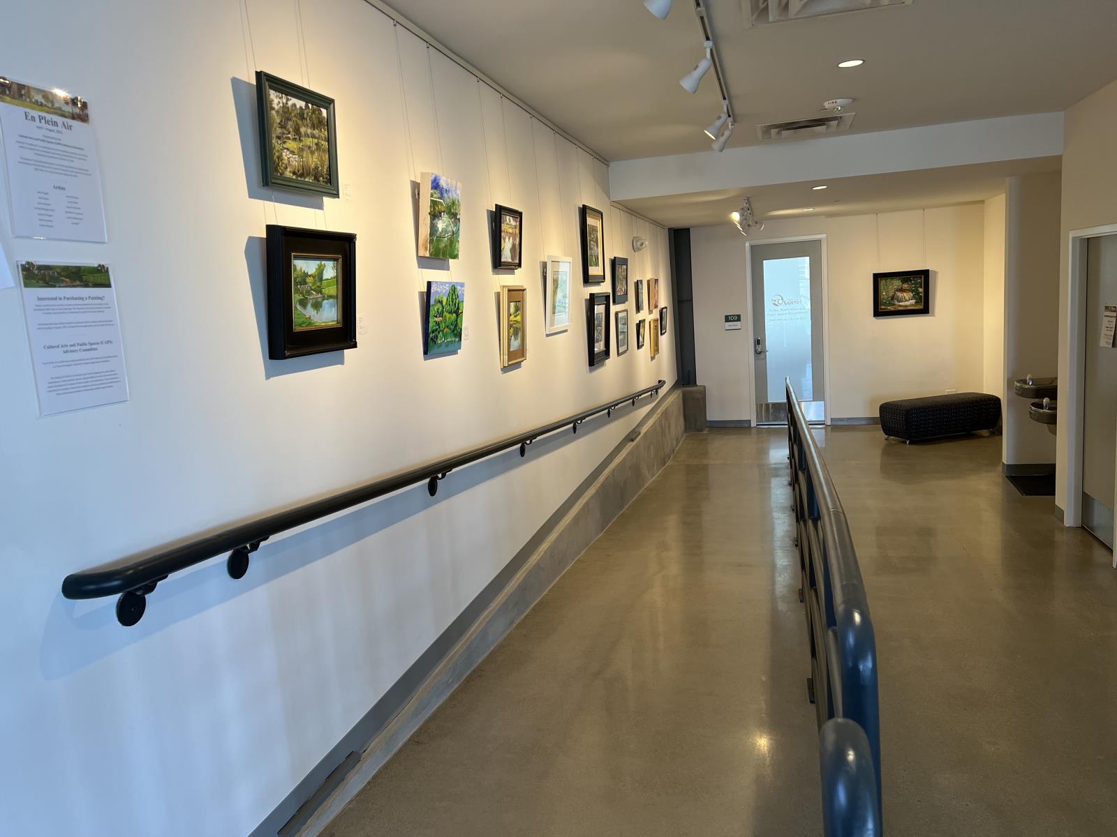 Artworks of the 2022 Plein Air exhibit lining a hallway in the Superior Community Center.